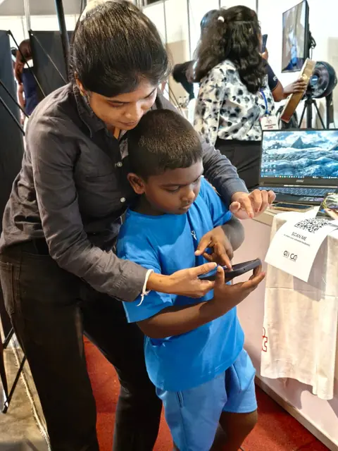 A team member guiding a young visitor through an activity on a phone
