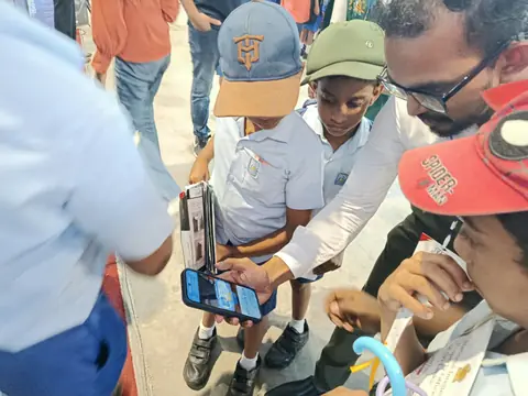 A group of young visitors watching a phone demonstration at the exhibition